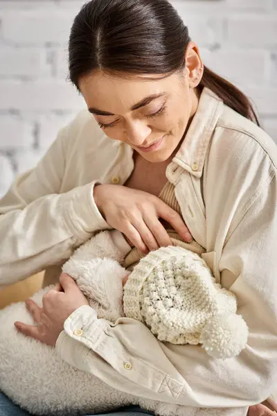 Bell'aspetto amorevole madre allegra in accogliente casalinghi che allattano il suo bambino appena nato, genitorialità moderna — Foto stock