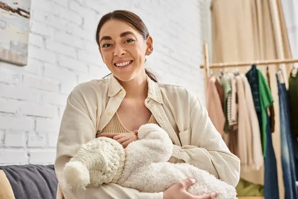 Attraktive fürsorgliche fröhliche Mutter in gemütlicher Hauskleidung, die ihr neugeborenes Kind stillt, moderne Elternschaft — Stockfoto