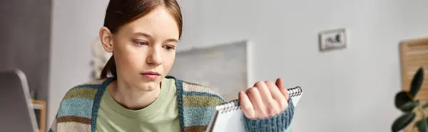 Teenage girl focused on her notes in her notebook while doing homework, horizontal banner — Stock Photo