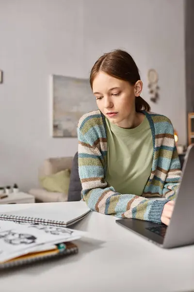 Teen girl engaged in e-learning with her notebook and laptop at a cozy home setting, digital age — Stock Photo
