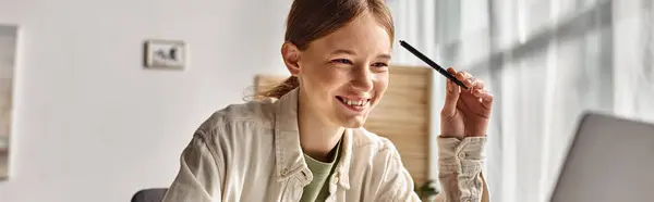Банер позитивного підлітка, який робить домашнє завдання на ноутбуці в домашньому середовищі, зосередитися на gen z дівчина — стокове фото