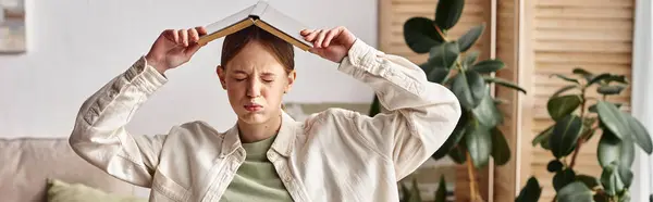 Overwhelmed teenage girl with a book on her head sitting in front of a laptop at home, banner — Stock Photo