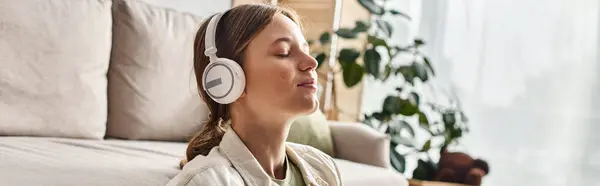 Carefree teenage girl in her wireless headphones listening music and holding cup of tea, banner — Stock Photo