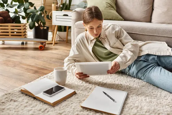 Дівчина-підліток тримає планшет біля чашки чаю, роблячи домашнє завдання, цифрова концепція — стокове фото