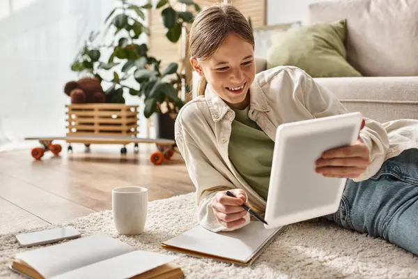 Happy teenage girl holding tablet and taking notes while making her homework, digital native concept — Stock Photo