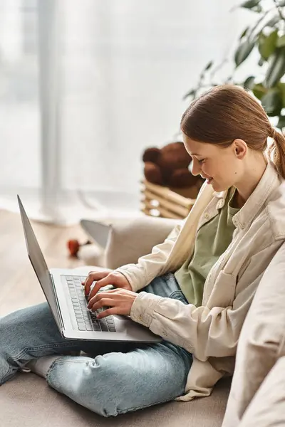 Happy teenage girl focused on e-learning using  her laptop and sitting on a comfortable sofa at home — Stock Photo