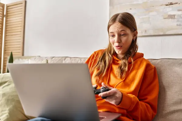 Erstaunte Teenager-Mädchen spielen mit Steuerknüppel und Laptop, während sie zu Hause auf dem Sofa sitzen, Wochenende-Stimmung — Stockfoto