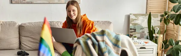 Focus sur adolescent fille assis avec son ordinateur portable près flou drapeau arc-en-ciel lgbt sur le bureau, bannière — Photo de stock