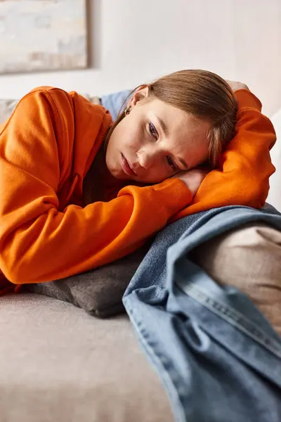 Depressed young girl lying on sofa in living room, solitude and melancholy of teenager concept — Stock Photo