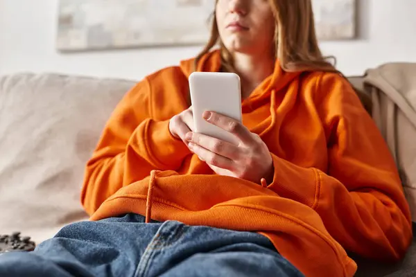 Plan recadré de l'adolescente en utilisant son smartphone et assis sur le canapé dans le salon, les médias sociaux — Photo de stock