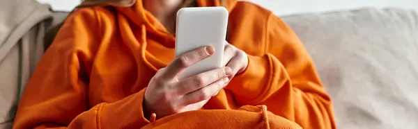 Cropped view of teenager browsing smartphone and sitting on the sofa at home, horizontal banner — Stock Photo