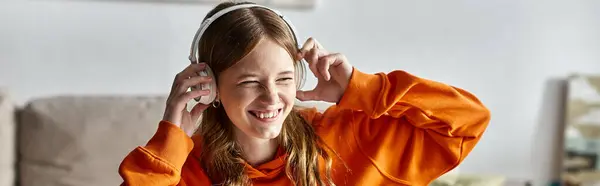 Радостная девочка-подросток в беспроводных белых наушниках наслаждается музыкой дома, горизонтальным баннером — стоковое фото