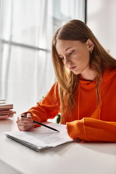 Pensive teenage girl drawing a sketch, immersed in creative process while sitting at desk — Stock Photo