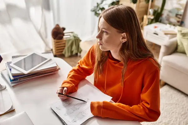 Nachdenkliches Teenager-Mädchen zeichnet eine Skizze, vertieft in den kreativen Prozess, während es zu Hause wegschaut — Stockfoto