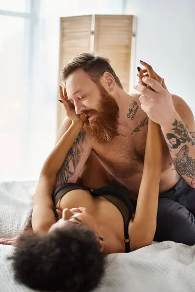 African american woman touching gently her tattooed boyfriend with beard in bedroom, intimate — Stock Photo