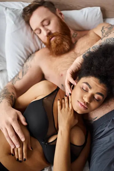 Tatuado e barbudo homem gentilmente tocando rosto de afro-americano namorada em lingerie no quarto — Fotografia de Stock