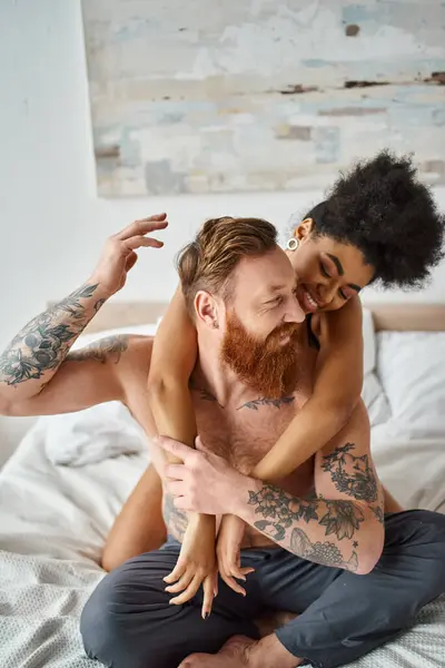 Heureux couple diversifié, frisé afro-américaine femme embrassant son petit ami tatoué dans la chambre — Photo de stock