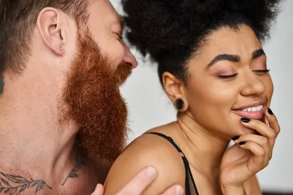 Bearded man with tattoos seducing happy african american woman in lingerie, diverse couple — Stock Photo