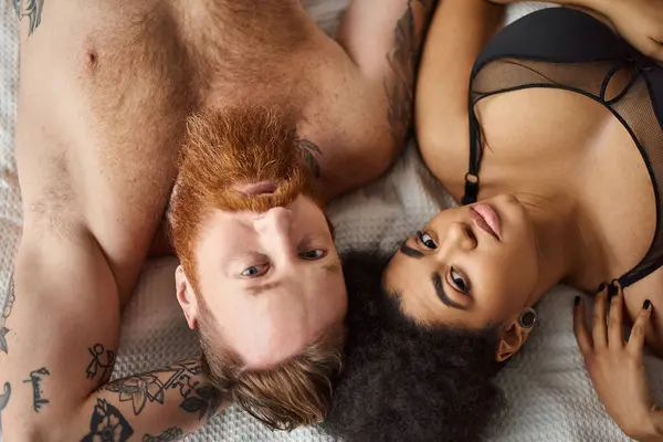Top view of diverse couple lying close on bed, intimate and connected bearded man and black woman — Stock Photo