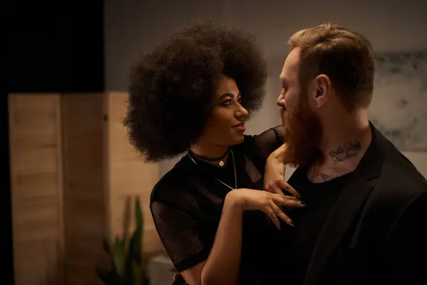 African american woman with curly hair in dress seducing tattooed boyfriend with beard, date night — Stock Photo