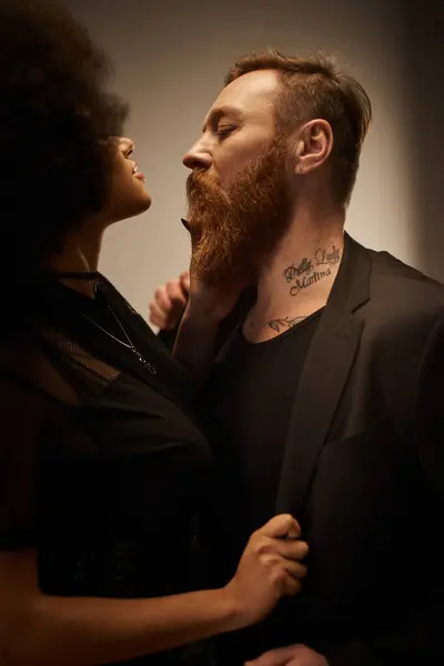 Ricci donna afroamericana in abito nero sedurre fidanzato tatuato con barba, data notte — Foto stock