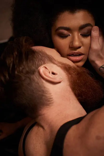 Barbuto uomo con tatuaggi toccare faccia di riccio africano americano donna mentre sedurre il suo su letto — Foto stock
