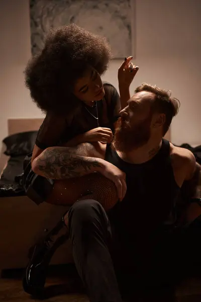 Bearded man with tattoos sitting near african american girlfriend in fishnet tights with rhinestones — Stock Photo