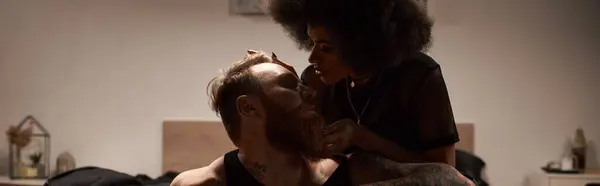 African american woman seducing her boyfriend with beard and tattoos in dark bedroom, banner — Stock Photo