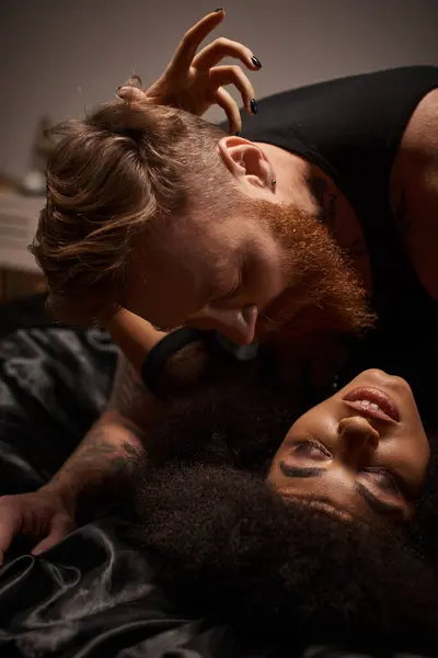 Passionate moment of multicultural couple making love on bed, man looking at african american woman — Stock Photo