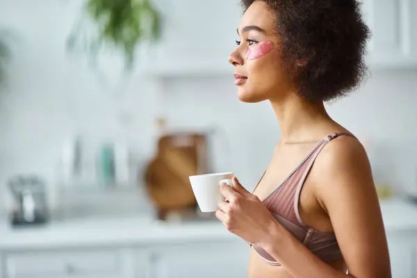 Peaceful african american woman with eye patches standing in underwear and enjoying morning coffee — Stock Photo
