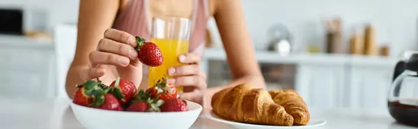 Cropped banner of african american woman holding fresh strawberry and orange juice during breakfast — Stock Photo