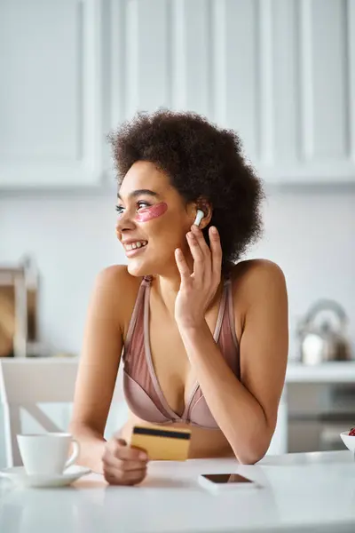 African american woman in earphones with patches under eyes shopping online with credit card — Stock Photo