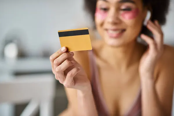 Donna afroamericana offuscata in auricolari shopping da casa con la sua carta di credito — Foto stock