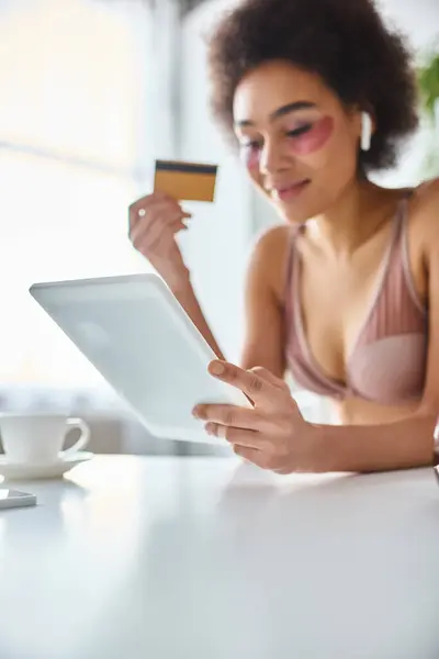 Femme afro-américaine gaie faisant du shopping en ligne avec tablette avec carte à la main et café de côté — Photo de stock