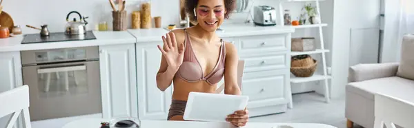 Happy african american woman in lingerie and eye patches having video call in kitchen, banner — Stock Photo