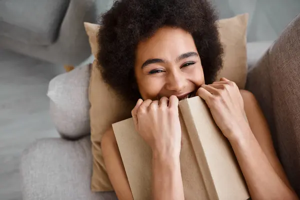 Top view of excited african american woman underwear lying with open book on a comfy sofa — Stock Photo