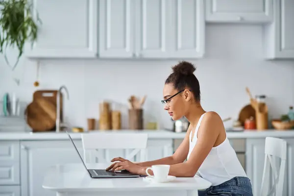 Vue latérale de frisée afro-américaine dans des lunettes de travail de la maison sur son ordinateur portable, entrepreneur — Photo de stock