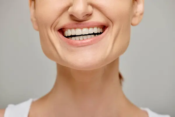 Vue recadrée de femme excitée exsudant sourire joyeux et sain sur fond gris, dents blanches — Photo de stock
