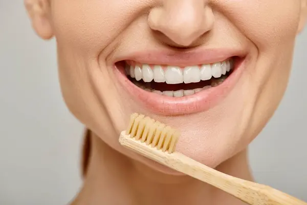 Photo recadrée de femme heureuse dans les années 30 avec des dents blanches saines tenant une brosse à dents en bambou, dentaire — Photo de stock