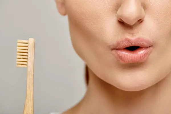 Cropped shot of surprised woman in 30s holding a bamboo toothbrush, face expression — Stock Photo