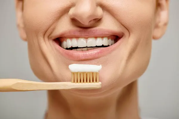 Ausgeschnittene Ansicht einer glücklichen Frau, die Zahnbürste mit Zahnpasta in der Hand hält und in die Kamera lächelt — Stockfoto