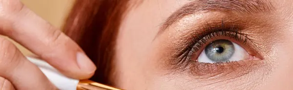 Bannière de gros plan, femme rousse appliquant des paillettes scintillantes sur la joue avec pinceau de maquillage sur beige — Photo de stock