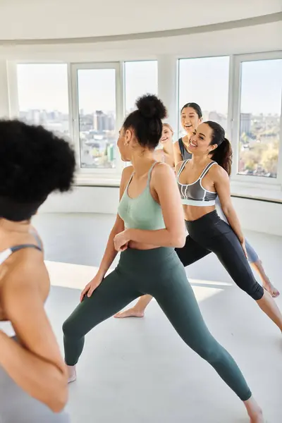 Groupe de femmes heureuses et diversifiées en leggings pratiquant pilates avec entraîneur afro-américain féminin — Photo de stock