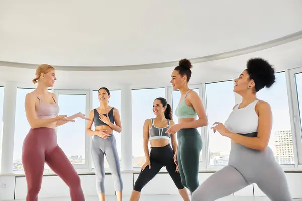 Group of cheerful diverse women in leggings and crop tops practicing pilates together with trainer — Stock Photo