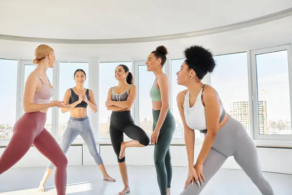 Group of happy interracial women in leggings and crop tops practicing pilates together with trainer — Stock Photo