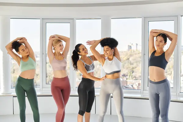 Feliz feminino pilates treinador ajudando mulher afro-americana com seu exercício de alongamento em estúdio — Fotografia de Stock