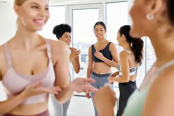 Centrarse en las amigas en la ropa deportiva de chat, mientras que de pie en ropa deportiva antes de la clase de pilates - foto de stock