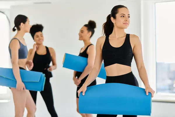 Focus on brunette young woman in sportswear standing with fitness mat in pilates studio — Stock Photo