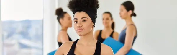 Focus on african american woman standing with fitness mat in yoga studio, horizontal banner — Stock Photo