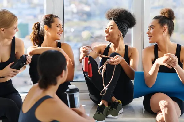 Gruppe fröhlicher und junger interrassischer Frauen in aktiver Kleidung plaudert nach dem Training im Pilates-Studio — Stockfoto